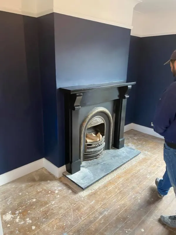 a man standing next to a fireplace in a room