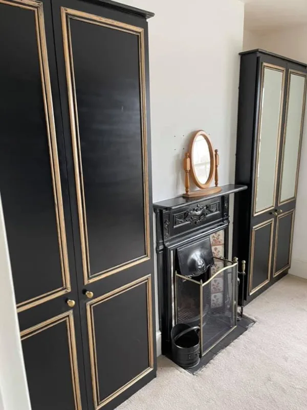a room with a black and gold armoire and a mirror